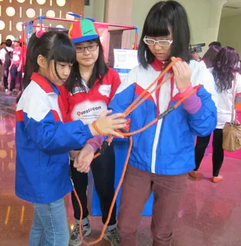 Các học sinh nữ thích thú trò "còng tay". Đeo một đôi còng tay, nhờ một bạn khác cũng đeo một đôi khác để hai bạn kết nối lại như nhau.