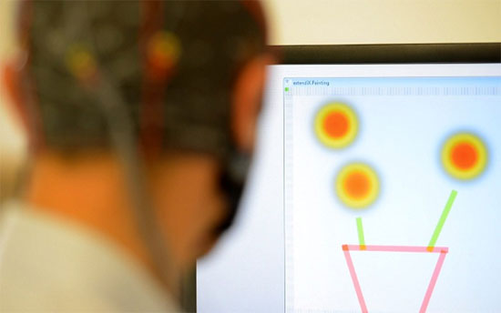 Một tình nguyện viên đội mũ điện cực để điều khiển máy tính vẽ tranh.