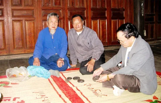 Ông Vi Văn Biến đang khoe các hiện vật cổ của mình với khách
