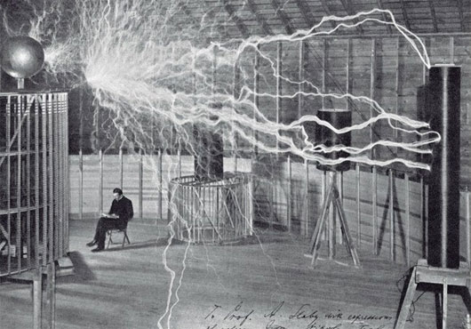 Nikola Tesla trong phòng thí nghiệm với các cuộn dây truyền tải điện hàng triệu volt qua không khí.