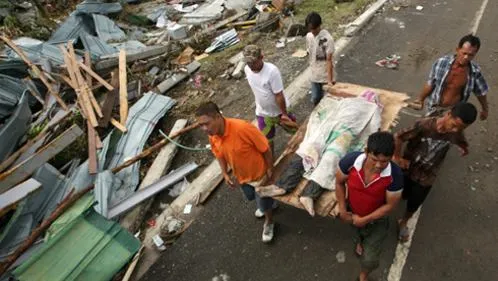 Người sống sót khiêng một xác người chết trong khung cảnh tiêu điều ở Tacloban