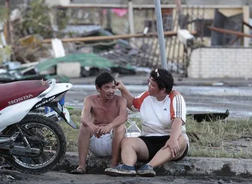 Hai người ngồi động viên nhau bên ngoài ngôi nhà đổ nát của họ ở Tacloban