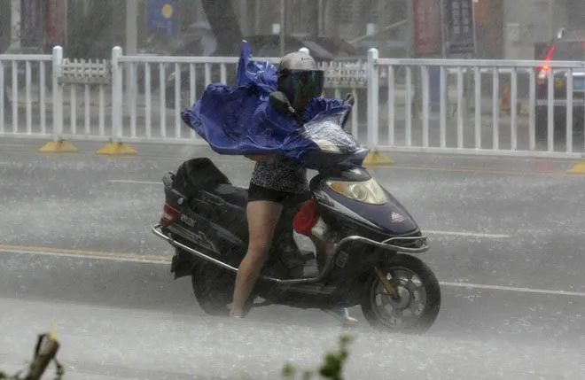 Một phụ nữ ở thành phố Trạm Giang, tỉnh Quảng Đông, vất vả lái xe dưới cơn mưa lớn và gió mạnh do bão gây ra.