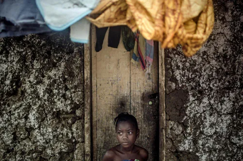 Cô bé Messi Boa ngồi buồn bã trước cửa nhà ở làng Njala Ngiema, Sierra Leone sau khi bố mẹ em qua đời vì nhiễm virus Ebola.