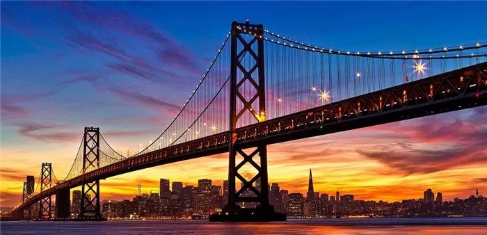 Nền trời chuyển từ xanh sang vàng báo hiệu hoàng hôn đang buông xuống trên cầu vịnh Oakland - San Francisco.