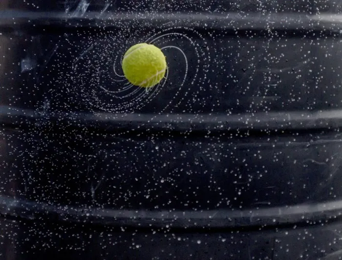 Trái banh tennis đẫm nước được đánh đi ở tốc độ cao