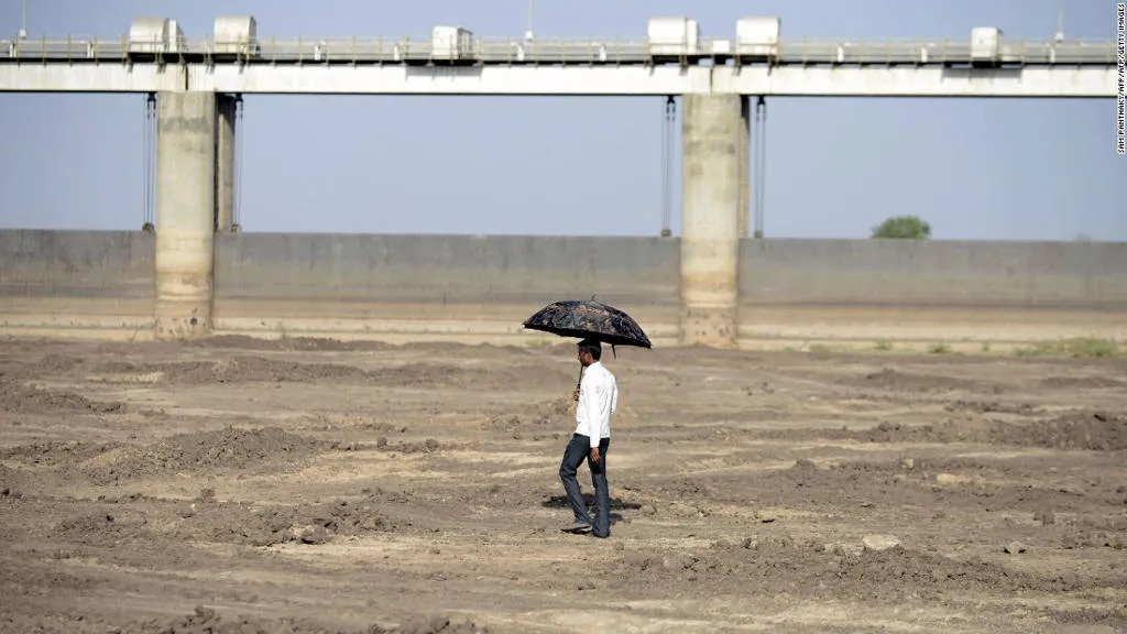 Người đàn ông đi bộ trong lòng hồ khô cạn ở làng Gunda Dam, miền tây Ấn Độ.