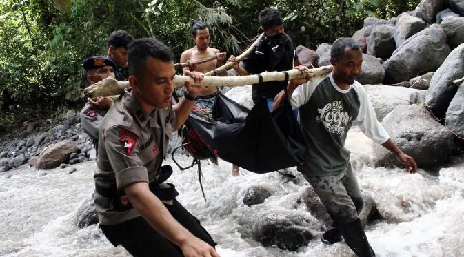 Cảnh sát Indonesia và dân làng di chuyển thi thể của một nạn nhân bị nước cuốn trôi.