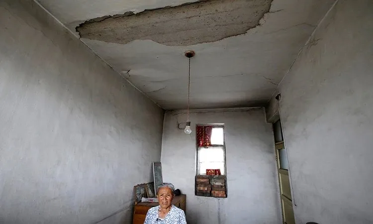 Bà Gao Xiuzhen, 81 tuổi, ngồi trong ngôi nhà hư hỏng cạnh một mỏ than ở làng Yongdingzhuang.