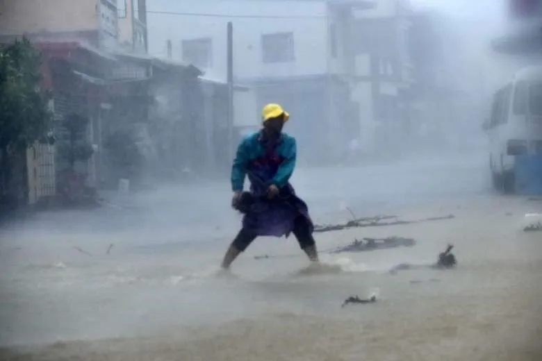 Một người dân ở huyện Bình Đông dọn dẹp đá và chướng ngại vật trên một con đường trong mưa bão.