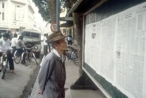 Một cụ già đọc báo dán tại một bảng tin trên phố Hàng Khay ở Hà Nội.