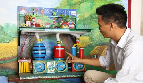 Thầy giáo Phạm Sơn Thu bên mô hình máy thu và xử lý bão trong lòng đất.
