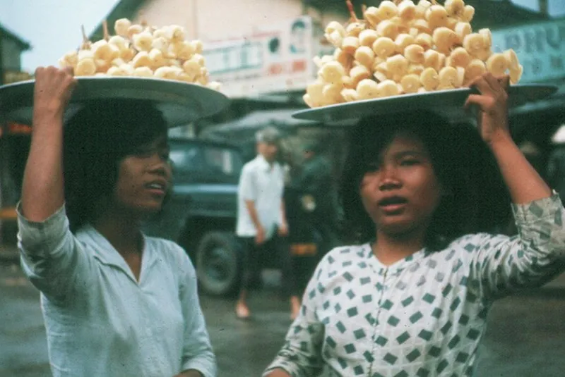 Hai cô bé đang đội mâm mía trên đầu đi bán.