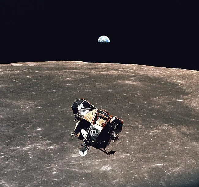 Thiết bị mô đun không gian của tàu Apollo 11 đáp xuống bề mặt mặt trăng, phía xa là Trái Đất.