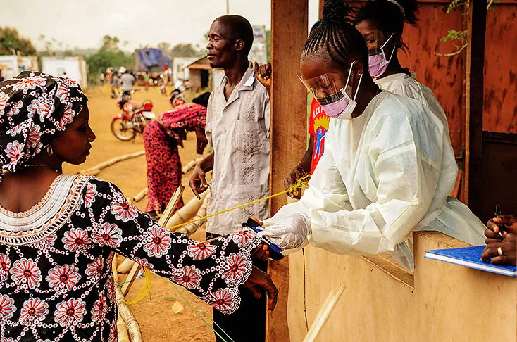 Nhân viên y tế Sierra Leone kiểm tra thân nhiệt của hành khách tại khu vực biên giới với Liberia ở Jendema