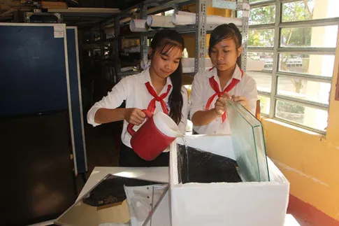 Thu Ngân (bên trái) và Yến Linh đưa nước mặn vào thử nghiệm hệ thống lọc.